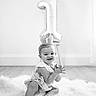 Gianna is registered to the contest to win money with this photo: baby, child, birthday, crown, balloon, number_one, smiling, sitting, portrait, black_and_white, indoors, rug, fluffy, dress, hands, celebration, milestone, photography, happy, infant