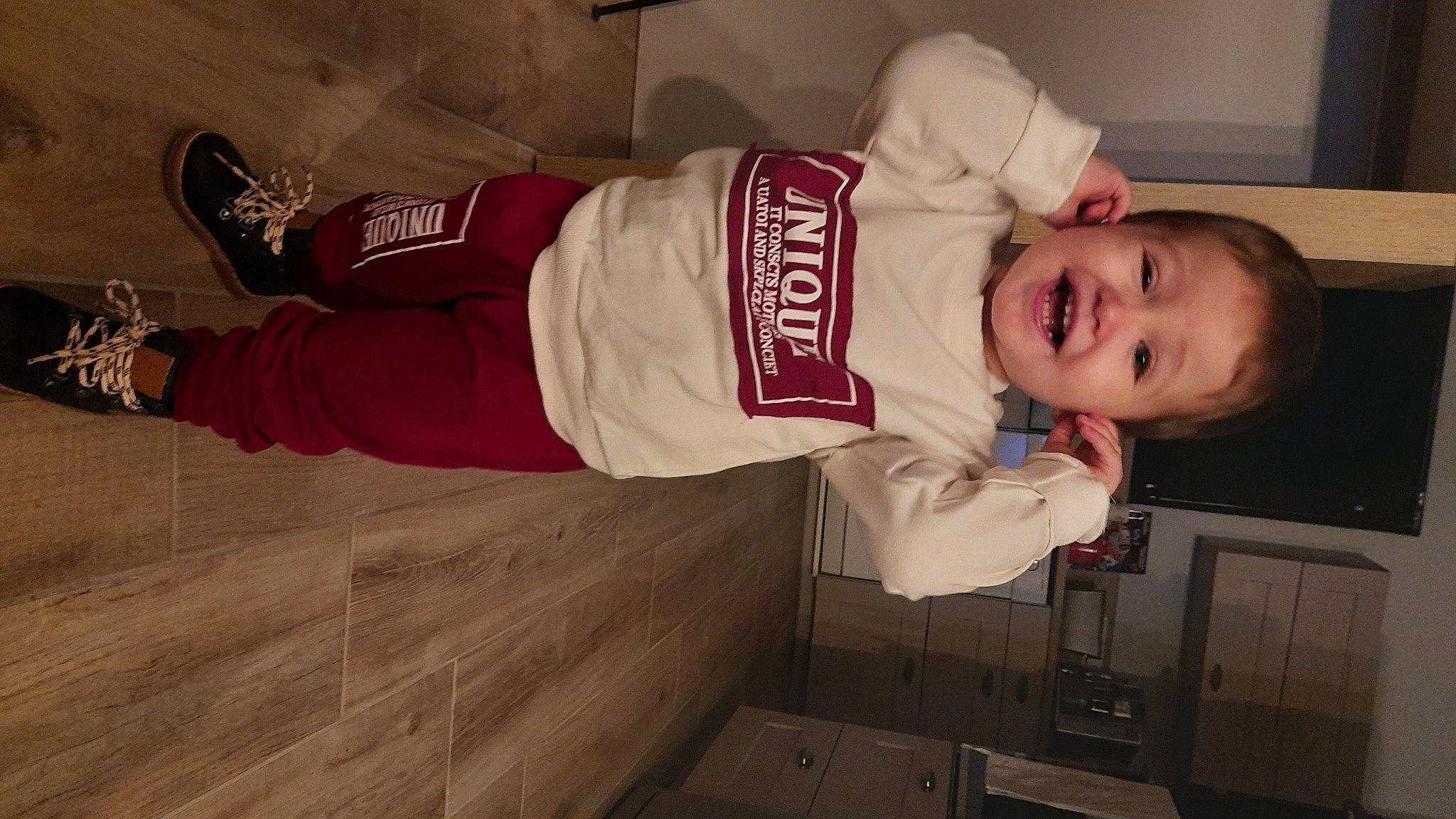 Maé participe au concours pour gagner de l'argent avec cette photo : baby, baby_laughing, baby_toddler_clothing, carmine, child, fun, happy, hardwood, hat, person, room, sleeve, smile, sportswear, toddler, uniform, walking_shoe, watch, wood