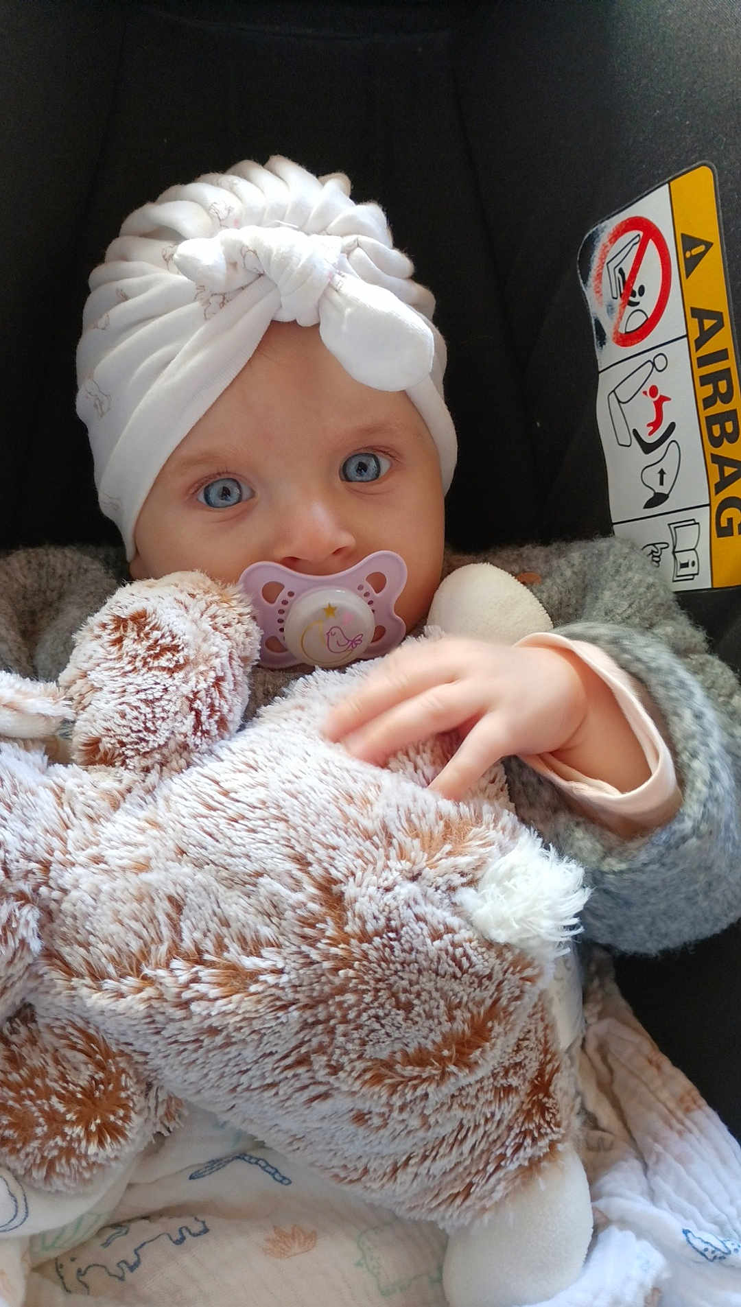 Elina a rejoint le concours — aidez-le/la à gagner de superbes lots ! baby, pacifier, stuffed_animal, hat, car_seat, airbag_warning, blue_eyes, hand, clothing, blanket, child, portrait, cute, infant, cozy, soft_toy, indoor, sitting, warm, young_child