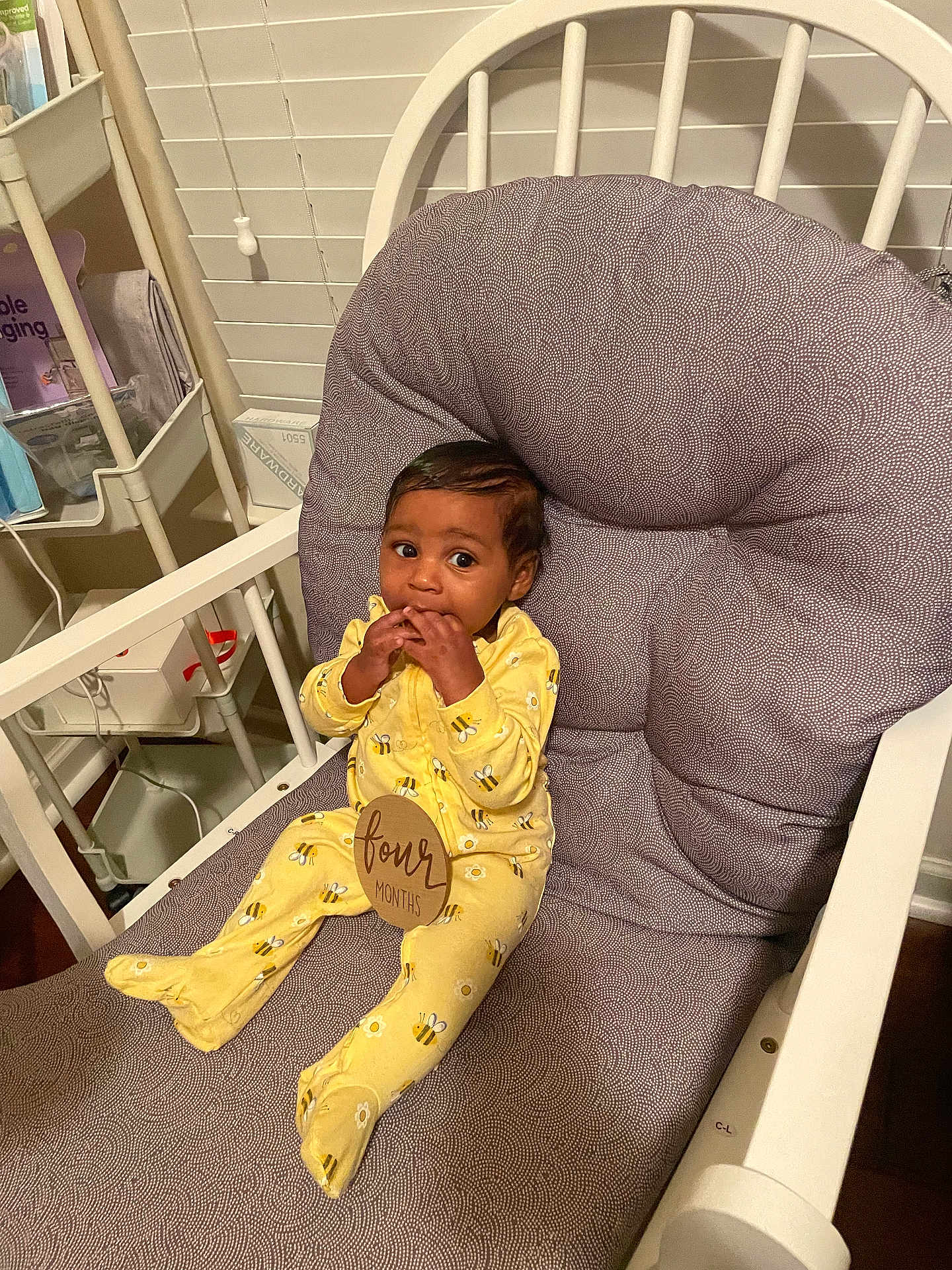 Trustin is registered to the contest to win money with this photo: baby, child, yellow_onesie, bee_pattern, cushioned_chair, indoor, infant, four_months, window_blind, sitting, fingers_in_mouth, curious, cute, wooden_chair, baby_clothing, home_interior, shelf, baby_accessories, smiling, portrait