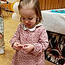 child, girl, dress, balloons, indoor, party, floor, wood_paneling, table, plate, curious, standing, long_sleeves, collar, young_child, light_brown_hair, footwear, tile_floor, background, event