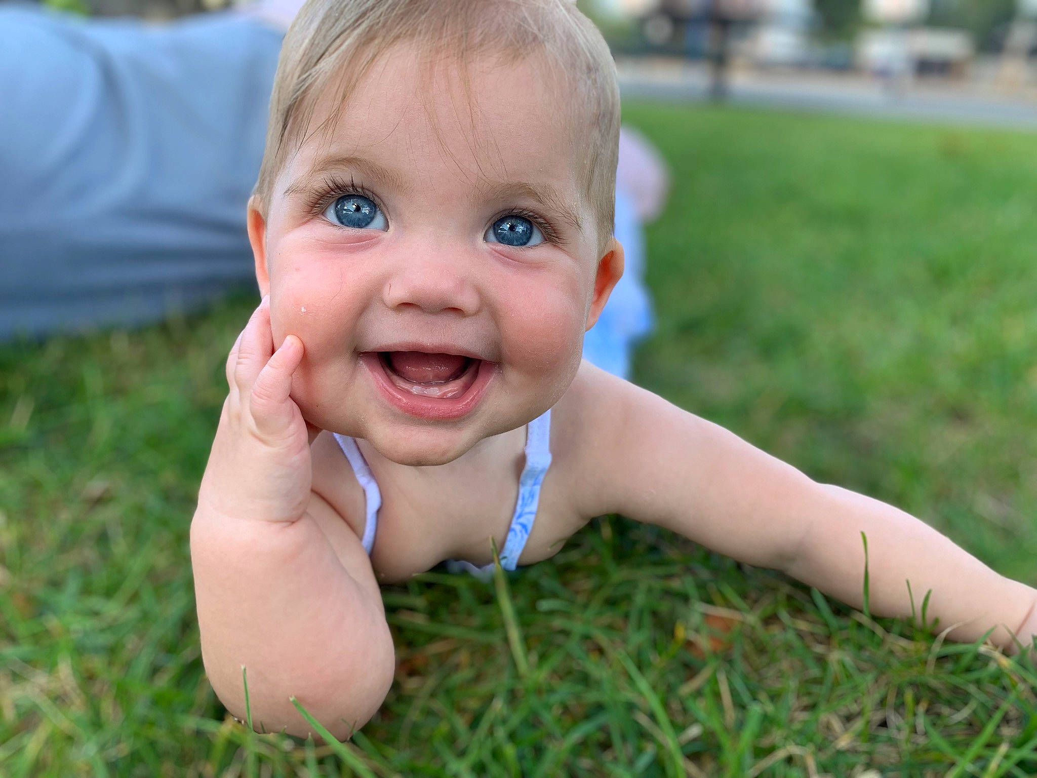Poppy is registered to the contest to win money with this photo: baby, dress, eye, finger, gesture, grass, hand, happy, human_body, iris, joy, leisure, lip, meadow, people_in_nature, person, plant, recreation, skin, smile