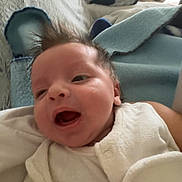 Gabriel participe au concours pour gagner de l'argent avec cette photo : baby, infant, smiling, mouth_open, onesie, blanket, pillow, bed, indoor, portrait, soft_toy, hair, cheek, skin, lying_down, cozy, happy, sleepwear, parent_arm, fabric