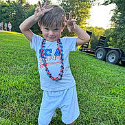 Whitley is registered to the contest to win money with this photo: child, boy, grass, outdoor, playful, beads, tshirt, usa, summer, nature, trees, sunset, trailer, sandals, smile, portrait, greenery, person, fun, cute