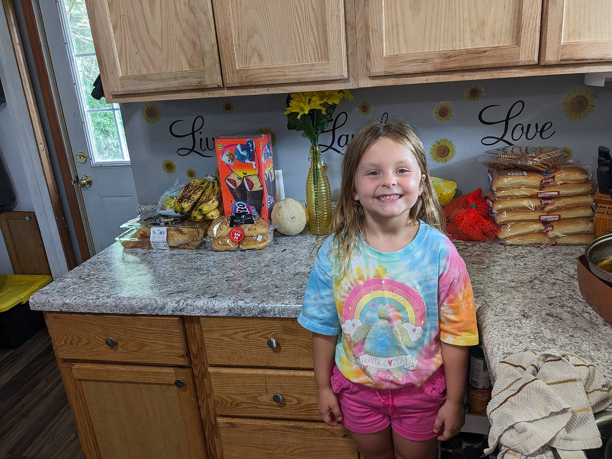 Shaelyn is registered to the contest to win money with this photo: cabinetry, child, cupboard, drawer, event, flooring, food, happy, hardwood, joy, kitchen, leisure, person, room, shorts, sitting, smile, table, tableware, vacation