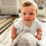 Maël participe au concours pour gagner de l'argent avec cette photo : arm, baby, blue_eyes, carpet, child, curly_hair, cute, elephant, floor, happy, home, indoor, playful, plush_toy, portrait, smiling, soft_toy, toddler, white_shirt, young_child