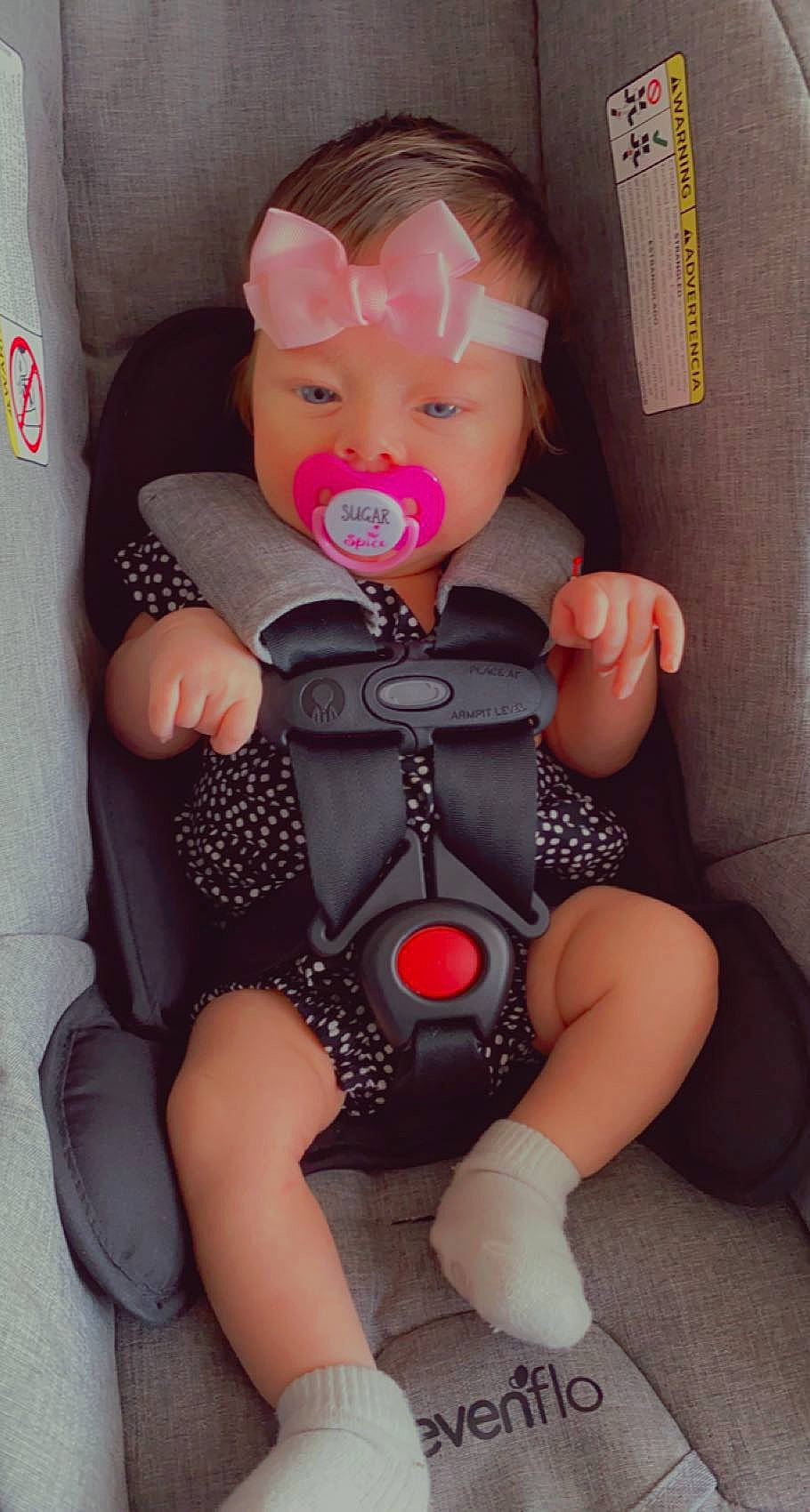 Valentina is registered to the contest to win money with this photo: baby_safety, baby_toddler_clothing, car_seat, cheek, comfort, doll, eye, finger, head, human_body, knee, lap, leg, nail, person, pink, skin, textile, thigh, toy