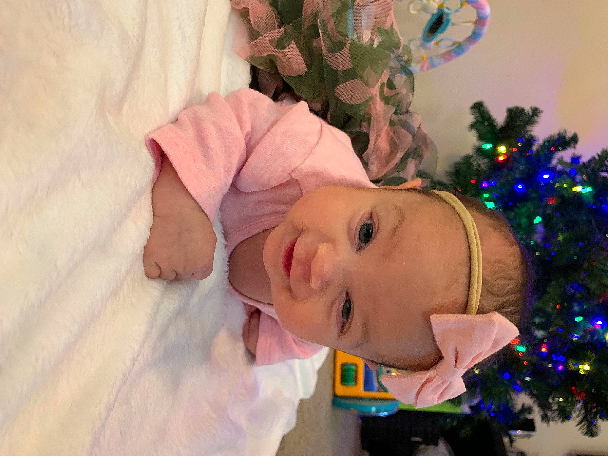 Daphne is registered to the contest to win money with this photo: baby, baby_toddler_clothing, child, christmas, christmas_decoration, christmas_eve, christmas_lights, christmas_ornament, christmas_tree, conifer, costume_accessory, facial_expression, fir, holiday, holiday_ornament, interior_design, laugh, ornament, person, pink