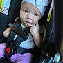 baby, blue_eyes, car_seat, child, clothing, cute, expression, face, hand, headwear, indoors, infant, person, pink_pants, portrait, safety, seatbelt, sitting, white_hat, young_child