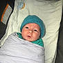 Leo is registered to the contest to win money with this photo: baby, blanket, blue_hat, pacifier, infant, face, wrapped, cushion, clothing, newborn, cute, indoors, child, soft, person, lying_down, warm, sleepy, toddler, car_seat