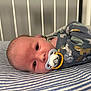 baby, infant, crib, pacifier, blanket, striped, onesie, animal_print, sleepwear, face, head, eyes, bed, nursery, cute, child, indoors, resting, soft_lighting, newborn