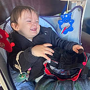 Gabriel participe au concours pour gagner de l'argent avec cette photo : baby, baby_seat, camo_pants, child, clothing, cute, face, furniture, hand, happy, helmet, indoor, jacket, pacifier, playful, relaxed, seat, smiling, toddler, toy