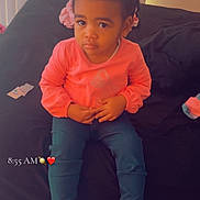 Zaharah is registered to the contest to win money with this photo: toddler, child, braided_hair, pink_shoes, pink_top, blue_pants, bed, black_bedspread, indoor, curtains, vertical_blinds, sitting, footwear, cute_shoes, expression, person, young_child, casual, home, timestamp