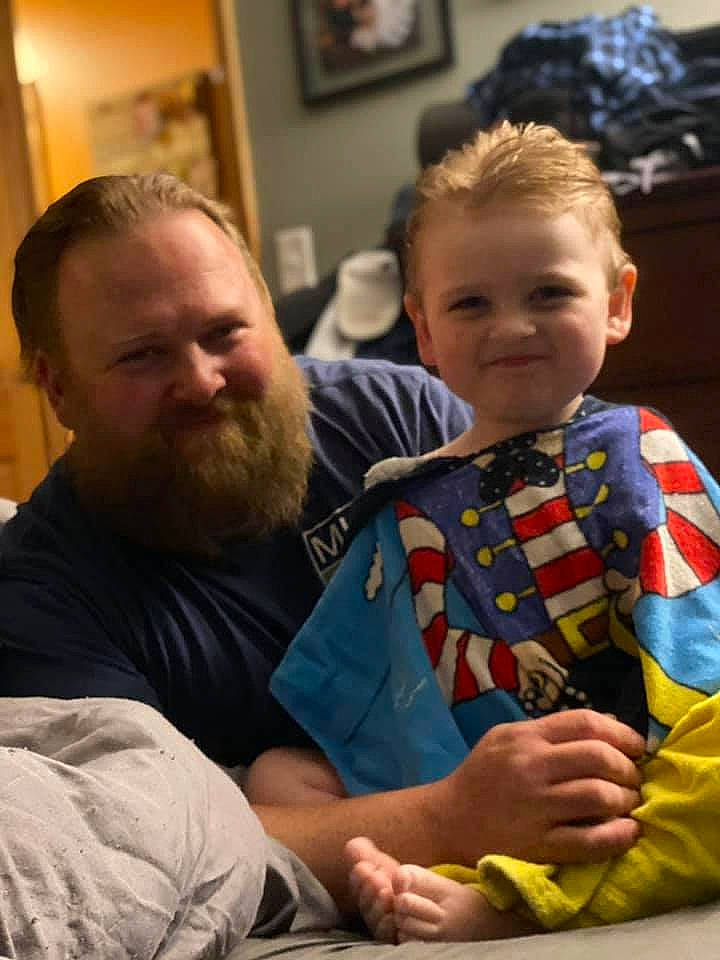 Gibson is registered to the contest to win money with this photo: beard, child, christmas, comfort, event, face, facial_expression, fun, happy, holiday, human, joy, lap, mammal, person, picture_frame, plaid, room, sitting, smile