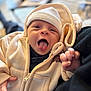apparel, baby, child, closeup, cozy, cute, expression, face, hand, hat, hoodie, indoors, infant, newborn, person, portrait, smile, soft_focus, tongue_out, warm_clothing