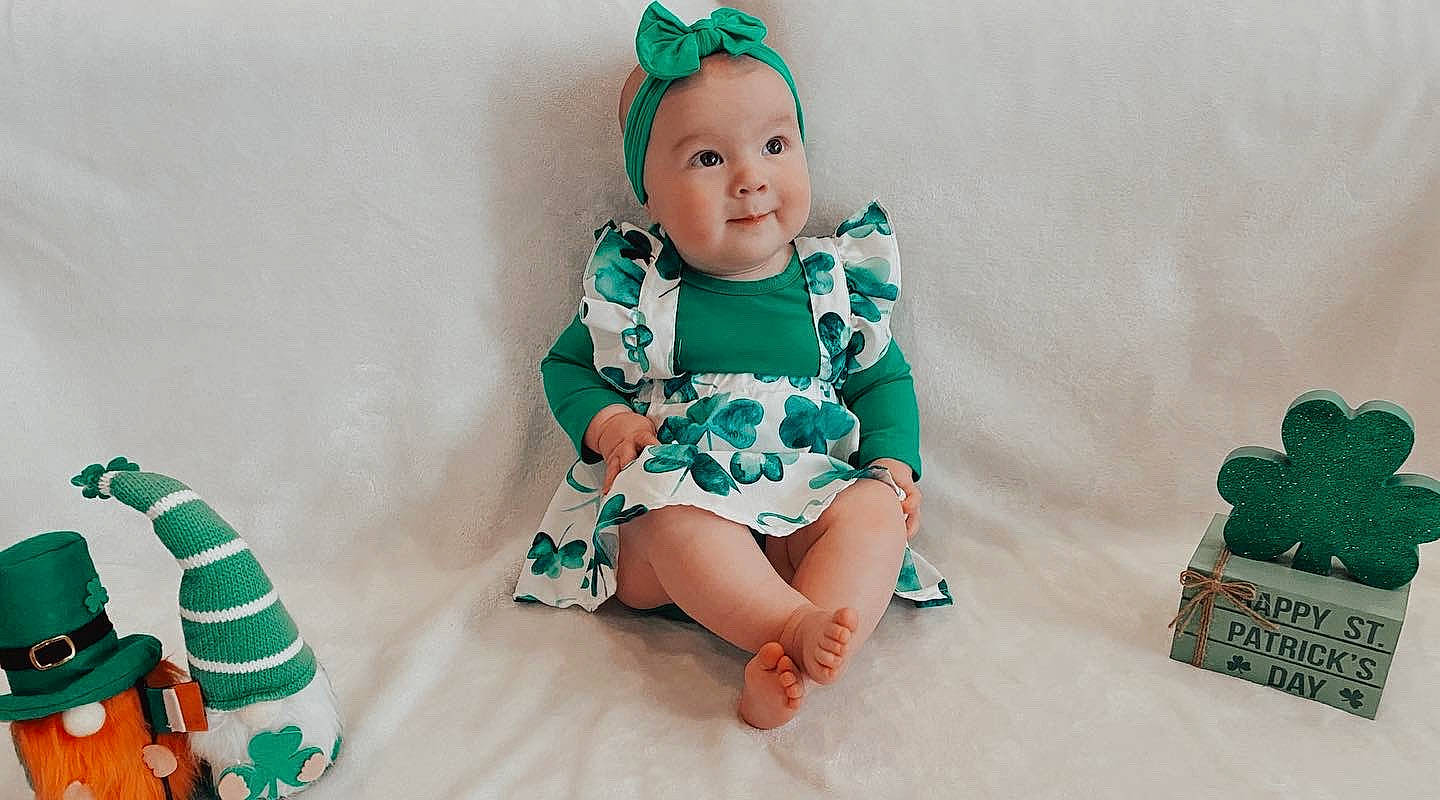 Trulee is registered to the contest to win money with this photo: aqua, baby, baby_toddler_clothing, child, costume_hat, dress, event, fashion_accessory, fictional_character, fun, grass, green, happy, headwear, holiday, pattern, person, sitting, sleeve, smile