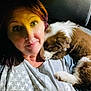 affection, car_interior, casual_clothing, closeup, cuddling, dim_lighting, dog, gray_shirt, indoor, nose_ring, pet, portrait, puppy, red_hair, relaxation, shoulder, sleeping_dog, smile, stars_pattern, woman