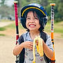 child, smiling, helmet, banana, baseball_bats, outdoor, sports, happy, person, short_sleeve_shirt, backpack, grinning, toy, play, summer, recreation, fun, youth, active, portrait