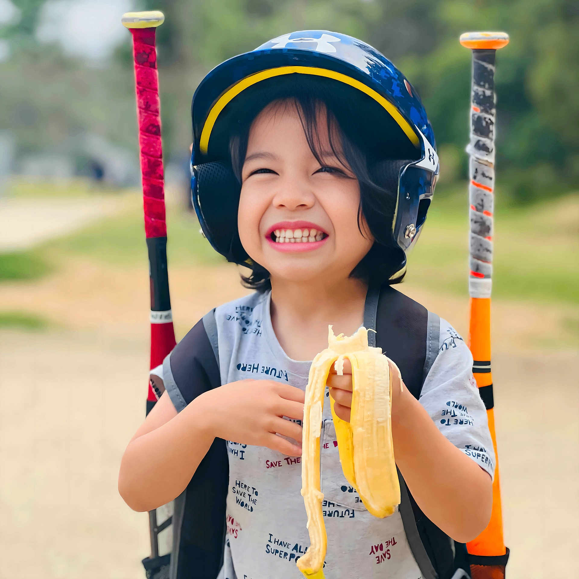 Zyrus is registered to the contest to win money with this photo: child, smiling, helmet, banana, baseball_bats, outdoor, sports, happy, person, short_sleeve_shirt, backpack, grinning, toy, play, summer, recreation, fun, youth, active, portrait