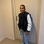 child, boy, standing, indoor, casual_clothing, backpack, sneakers, smiling, door, hallway, jacket, pants, person, hair_style, footwear, young, portrait, full_body, confident, light