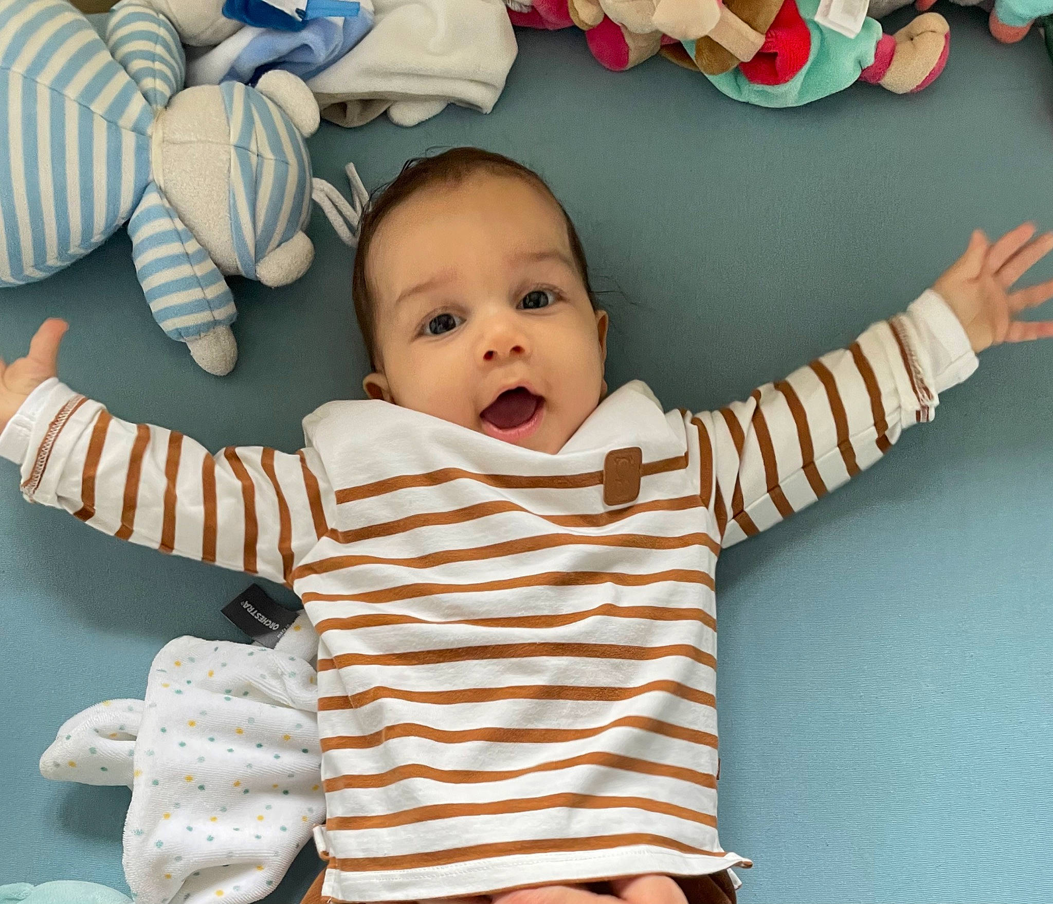 Emile a rejoint le concours — aidez-le/la à gagner de superbes lots ! baby, baby_products, baby_sleeping, baby_toddler_clothing, cheek, child, comfort, facial_expression, finger, gesture, happy, human_body, pattern, person, sitting, skin, sleeve, smile, thumb, toddler