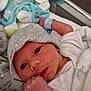 newborn, baby, hat, blanket, plush_toy, bunny, hospital_bracelet, bed, cute, infant, sleepwear, soft_toy, clothing, person, portrait, indoors, resting, child, face, hand
