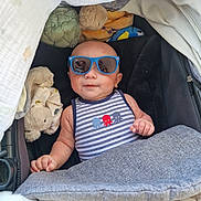 Teina-Enez participe au concours pour gagner de l'argent avec cette photo : baby, sunglasses, stroller, blanket, plush_toy, striped_clothing, infant, cute, relaxed, sleeping_bag, child, blue, comfort, casual, indoor, head, face, skin, hand, clothing