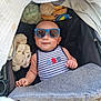 baby, sunglasses, stroller, blanket, plush_toy, striped_clothing, infant, cute, relaxed, sleeping_bag, child, blue, comfort, casual, indoor, head, face, skin, hand, clothing