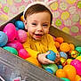 toddler, child, bunny_ears, easter_eggs, colorful, plastic_eggs, metal_container, yellow_clothing, smiling, happy, indoors, decorative_background, pink, blue, orange, green, holiday, festive, playful, cute