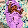 Hilani joined the competition — help win amazing prizes! adorable, baby, blanket, child, cute, expression, fabric, face, hand, happy, indoors, infant, lying_down, playful, purple, skin, smile, soft, towel, wrapped