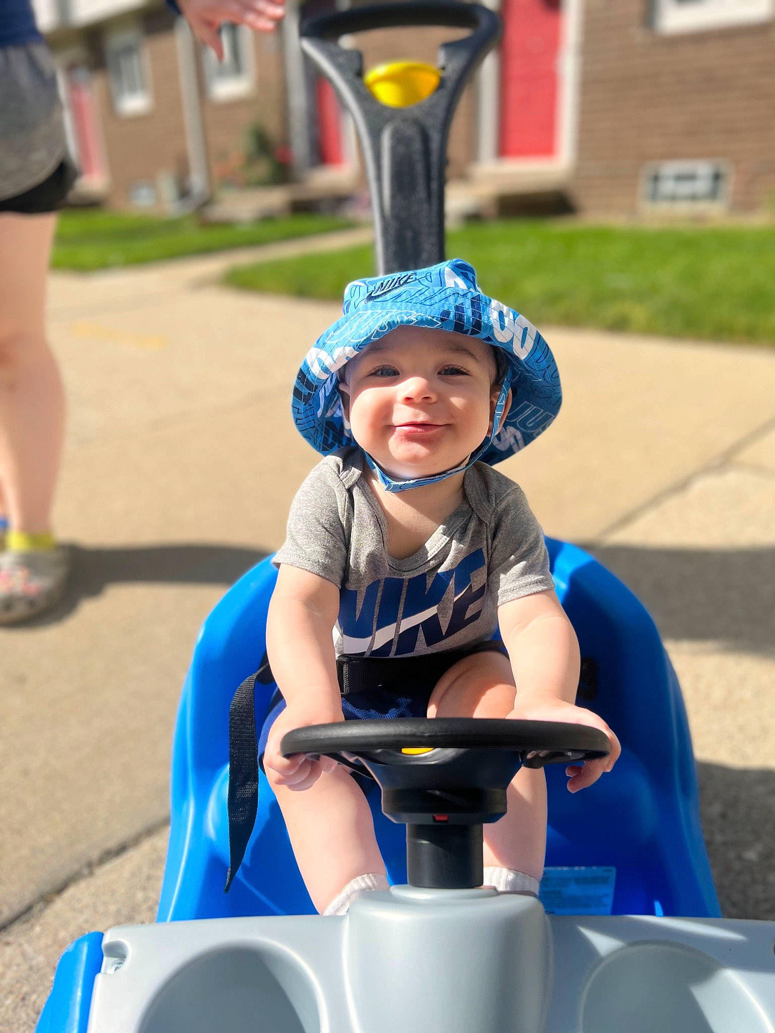 Jacoby is registered to the contest to win money with this photo: blue, boats_and_boating_equipment_and_supplies, child, city, electric_blue, fun, headwear, leisure, person, personal_protective_equipment, play, public_space, recreation, shorts, sitting, smile, snapshot, street_light, t_shirt, toddler