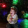 Aubrey is registered to the contest to win money with this photo: baby, child, smiling, happy, christmas_tree, christmas_lights, headband, wooden_floor, holiday, festive, infant, sitting, clothing, indoors, celebration, decorations, cute, joy, portrait, seasonal