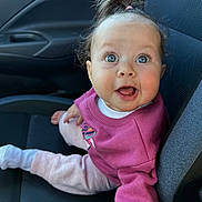 Aubrey joined the competition — help win amazing prizes! baby, child, car_seat, pink_sweater, pants, wide_eyes, surprised_expression, hair_tie, indoor, seat, clothing, portrait, cute, person, sitting, car_interior, childrens_clothing, smile, infant, young_child
