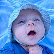 Nolan participe au concours pour gagner de l'argent avec cette photo : baby, blue_eyes, hat, blue_clothing, infant, close_up, face, cute, child, blanket, outdoor, expression, skin, person, newborn, portrait, hand, baby_gesture, headwear, young_child