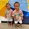 Ace joined the competition — help win amazing prizes! toddler, child, twins, matching_clothes, shorts, sandals, curly_hair, standing, colorful_background, wall_art, indoor, playful, smiling, portrait, cute, fashion, people, person, happy, casual