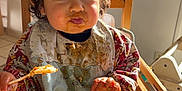 Marceau participe au concours pour gagner de l'argent avec cette photo : baby, bib, child, clothing, cute, dining, expression, face, feeding, food, hands, high_chair, indoor, meal, messy, plate, spoon, sunlight, toddler, wooden