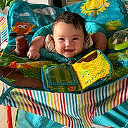 Isabella joined the competition — help win amazing prizes! baby, child, smiling, play_seat, toy, colorful, indoor, happy, face, curly_hair, infant, bright, patterned, seat, arms, fabric, cute, cheerful, playful, young