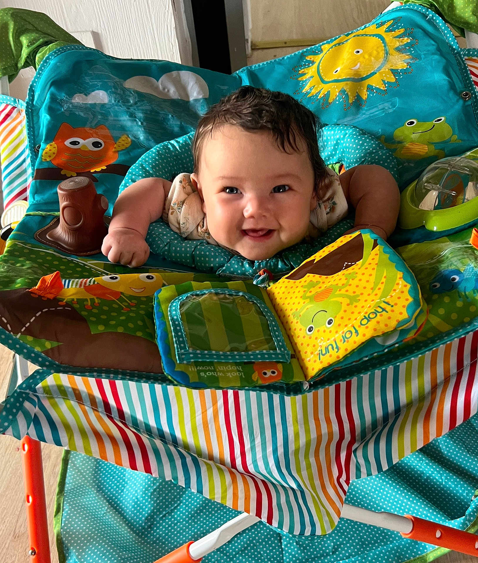 Isabella joined the competition — help win amazing prizes! baby, child, smiling, play_seat, toy, colorful, indoor, happy, face, curly_hair, infant, bright, patterned, seat, arms, fabric, cute, cheerful, playful, young