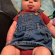 Kylynn joined the competition — help win amazing prizes! baby, baby_clothes, blanket, casual_clothing, child, closeup, cute, denim_overalls, headband, human, indoor, infant, legs, lying_down, pattern, person, playful, skin, smiling, tongue_out
