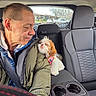 animal, backseat, car_interior, cozy, cuddle, cupholder, dog, happy, headrest, human, jacket, love, man, pet, seatbelt, small_dog, transportation, travel, warm_clothing, window