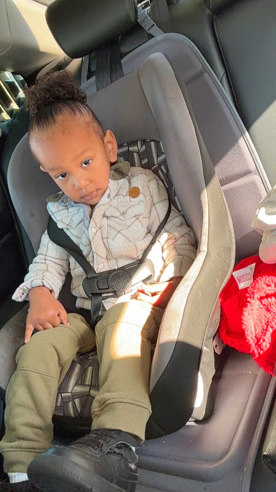 Skyler joined the competition — help win amazing prizes! child, toddler, car_seat, car_interior, seatbelt, plaid_jacket, olive_pants, black_shoes, high_puff_hairstyle, sunlight, window_light, seat, safety, young_child, portrait, casual_clothing, indoor, car, curious_expression, young_person