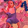 Filip participe au concours pour gagner de l'argent avec cette photo : baby, infant, knitted_clothing, purple_outfit, hat, blanket, cloud_pattern, pink_roses, blue_roses, flower_arrangement, letter_n, curious_expression, soft_texture, lying_down, cute, child, decorative_flowers, indoor, portrait, newborn