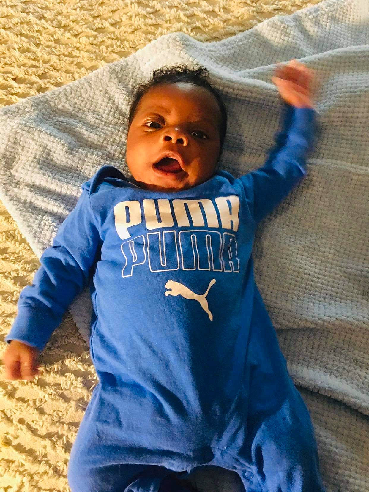 Malaki is registered to the contest to win money with this photo: azure, baby, baby_toddler_clothing, comfort, cool, electric_blue, eye, face, fun, happy, head, leisure, linens, person, product, sitting, sleeve, t_shirt, textile, toddler