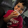 child, boy, smiling, curly_hair, red_shirt, sitting, couch, indoor, cup, drink, happy, portrait, young, casual_clothing, playful, hand, face, person, home, leather