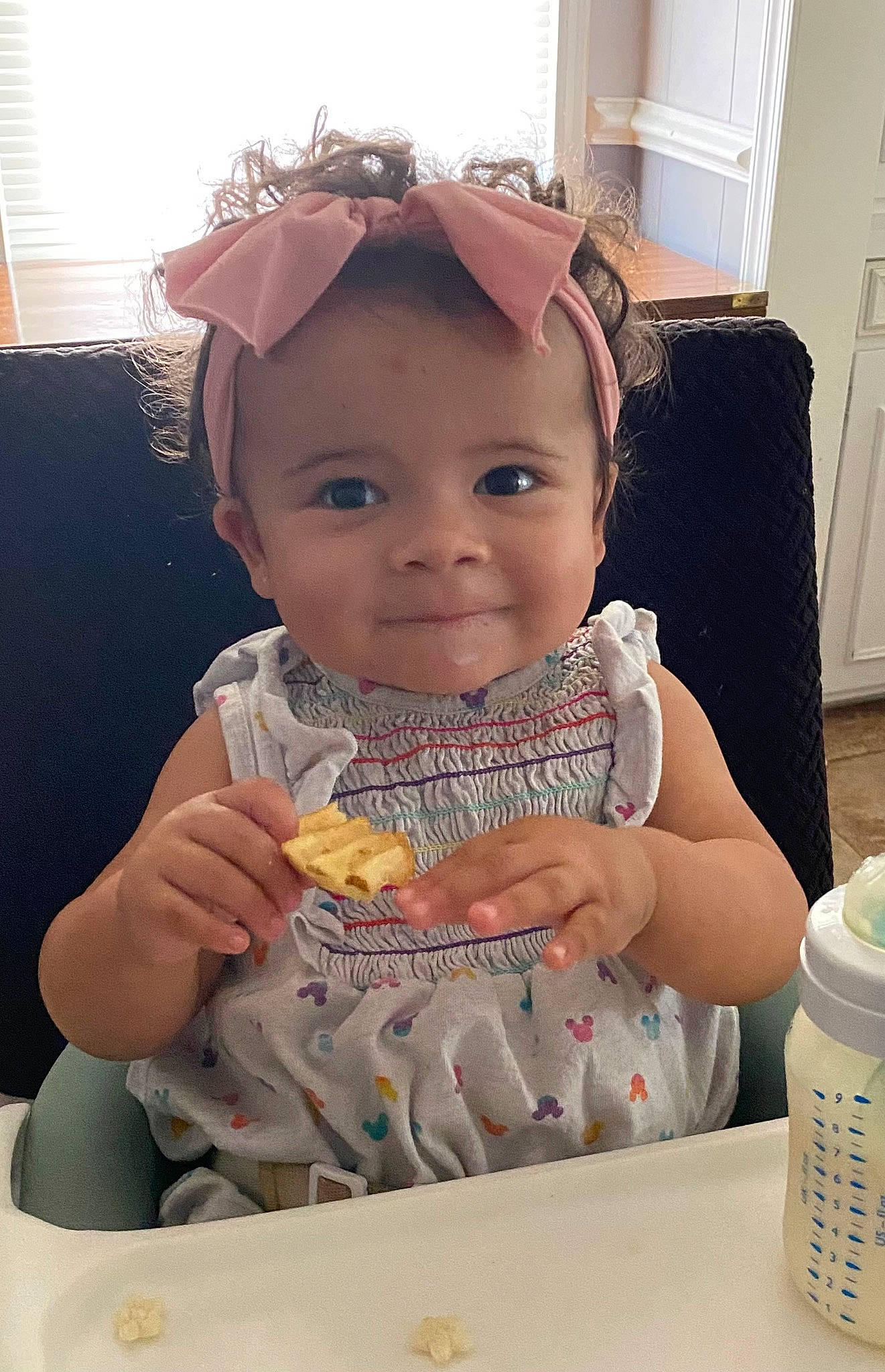 Sarai is registered to the contest to win money with this photo: baby, baby_toddler_clothing, bib, chair, child, comfort_food, door, drinkware, eating, eyewear, fashion_accessory, food_craving, happy, iris, person, personal_protective_equipment, skin, smile, t_shirt, toddler