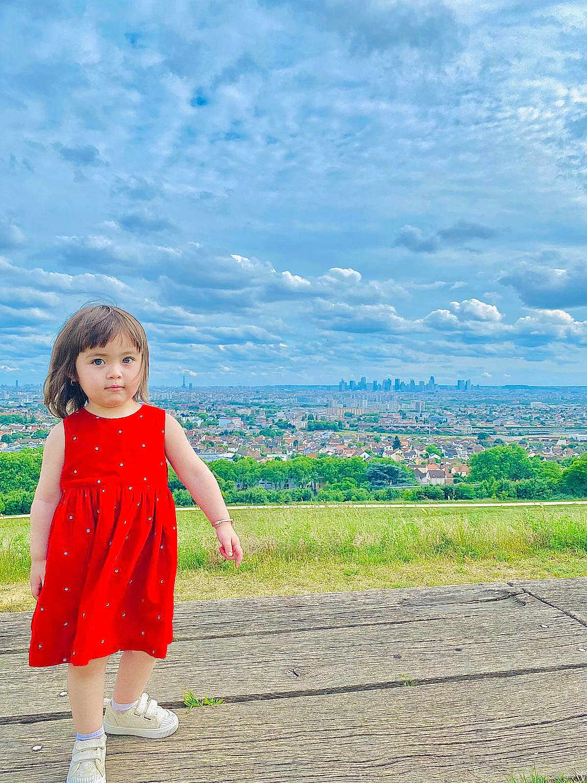 Moradi Zoya participe au concours pour gagner de l'argent avec cette photo : casual_shoes, child, cityscape, cloudy_sky, curious, daylight, girl, grass, greenery, nature, outdoor, person, portrait, red_dress, scenic_view, sky, standing, urban, wooden_platform, young