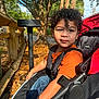 Clarence is registered to the contest to win money with this photo: boy, child, clothing, face, grass, gun, head, male, nature, outdoors, park, person, photography, plant, playarea, portrait, stroller, tree, vegetation, weapon