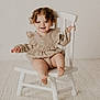 Charlotte joined the competition — help win amazing prizes! toddler, child, smiling, curly_hair, beige_clothing, white_chair, indoor, carpet, neutral_background, happy, cute, sitting, baby, portrait, furniture, young_child, playful, light, person, cozy