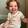 Charlotte is registered to the contest to win money with this photo: toddler, child, curly_hair, blue_eyes, smiling, pajamas, cat_pattern, sitting, floor, wooden_floor, indoor, happy, cute, portrait, baby, clothing, person, closeup, natural_light, home