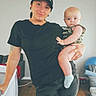 Ezra joined the competition — help win amazing prizes! adult, baby, black_tshirt, camouflage, cap, child, curious, floor, furniture, home, indoor, leggings, living_room, person, plush, pose, sock, tattoo, wood_floor, woman